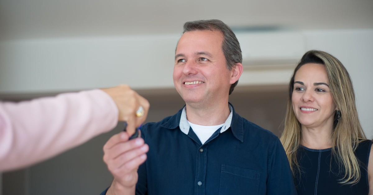 Smiling couple receiving keys, celebrating new home purchase indoors.