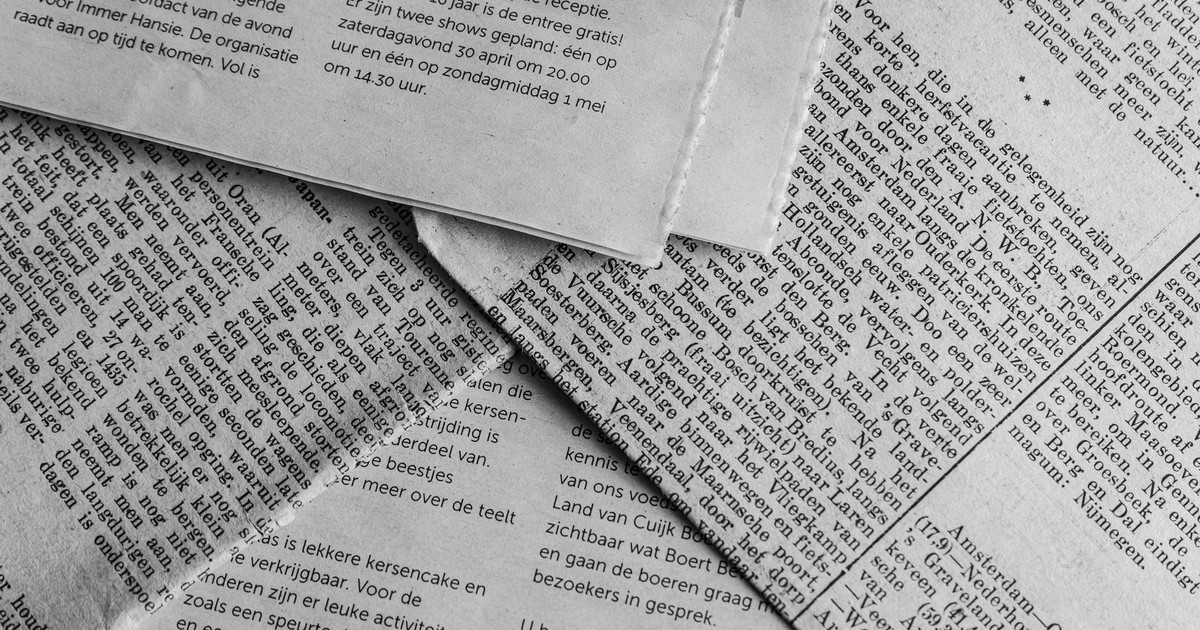 Black and white close-up of newspaper pages with text in Dutch.