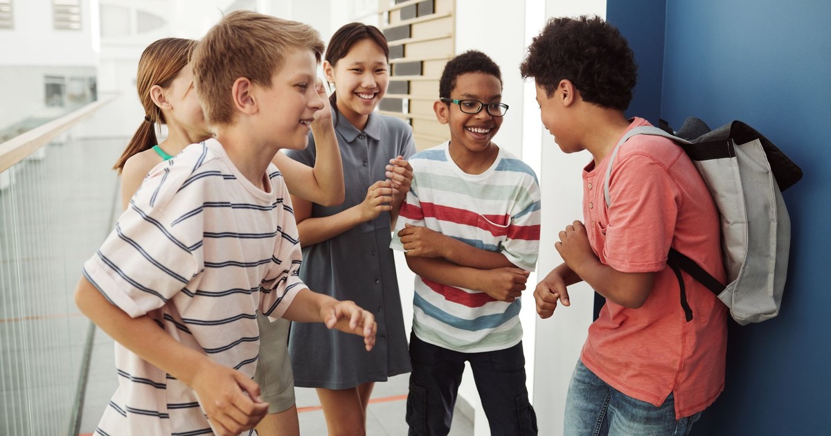 A happy group of diverse teenagers laughing and chatting in an indoor setting.