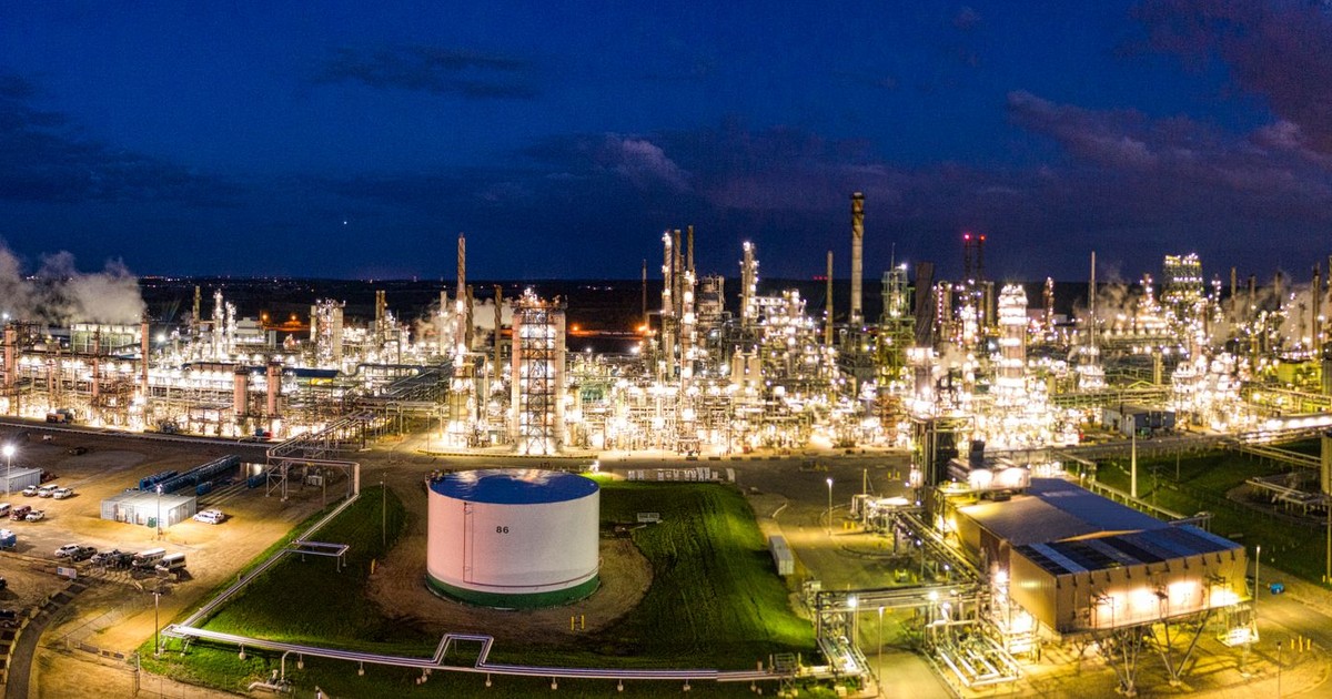 Aerial night view of a brightly lit industrial oil refinery with smoking chimneys in Rosemount, MN, USA.