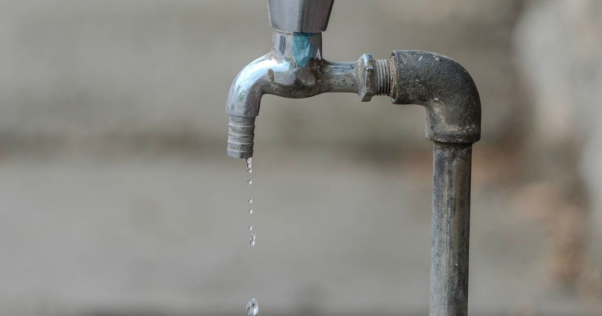 Close-up image of an outdoor water tap with a single droplet falling, highlighting water conservation.