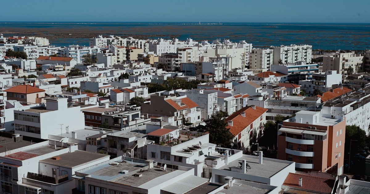Aerial view of Faro, Portugal cityscape with apartment buildings and ocean in the background.