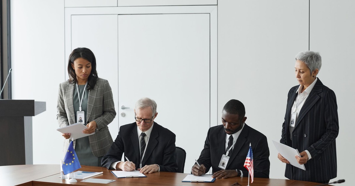 Business leaders signing a significant agreement in a conference room setting.