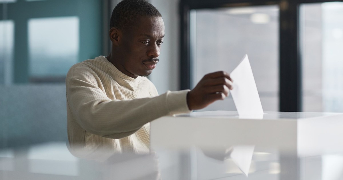A young man casting his vote at an indoor polling station, focused on the democratic process.