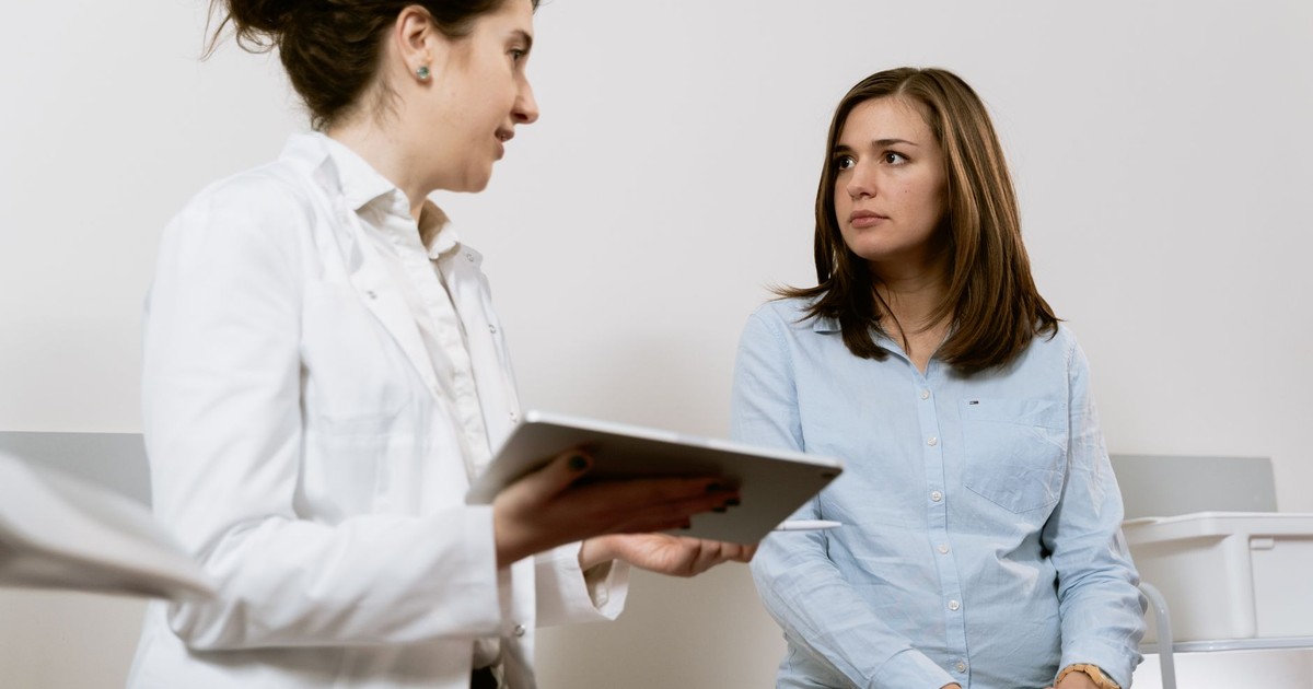 A doctor consults with a pregnant patient discussing healthcare options in a medical facility.