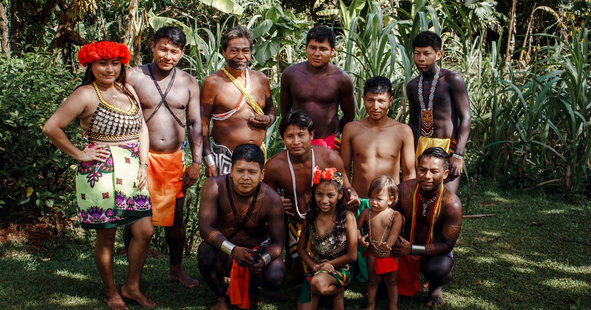 A diverse tribal group poses in a lush tropical forest.