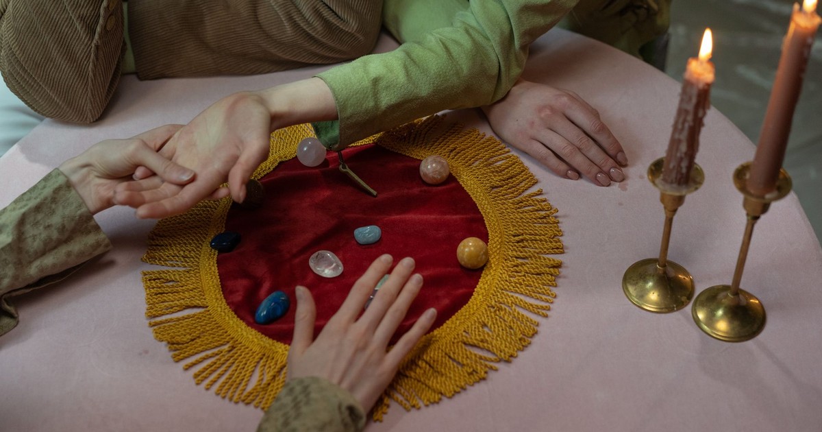Close-up of a fortune-telling session with crystals, candles, and palm reading.