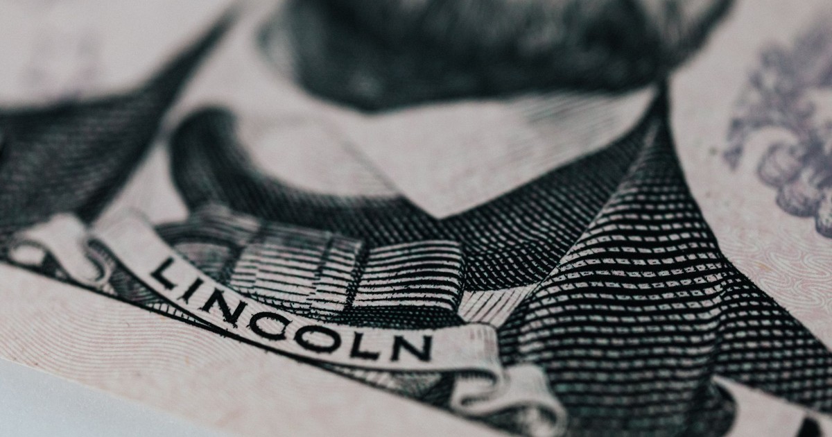 Crop of five dollar banknote with president Lincoln wearing costume on table