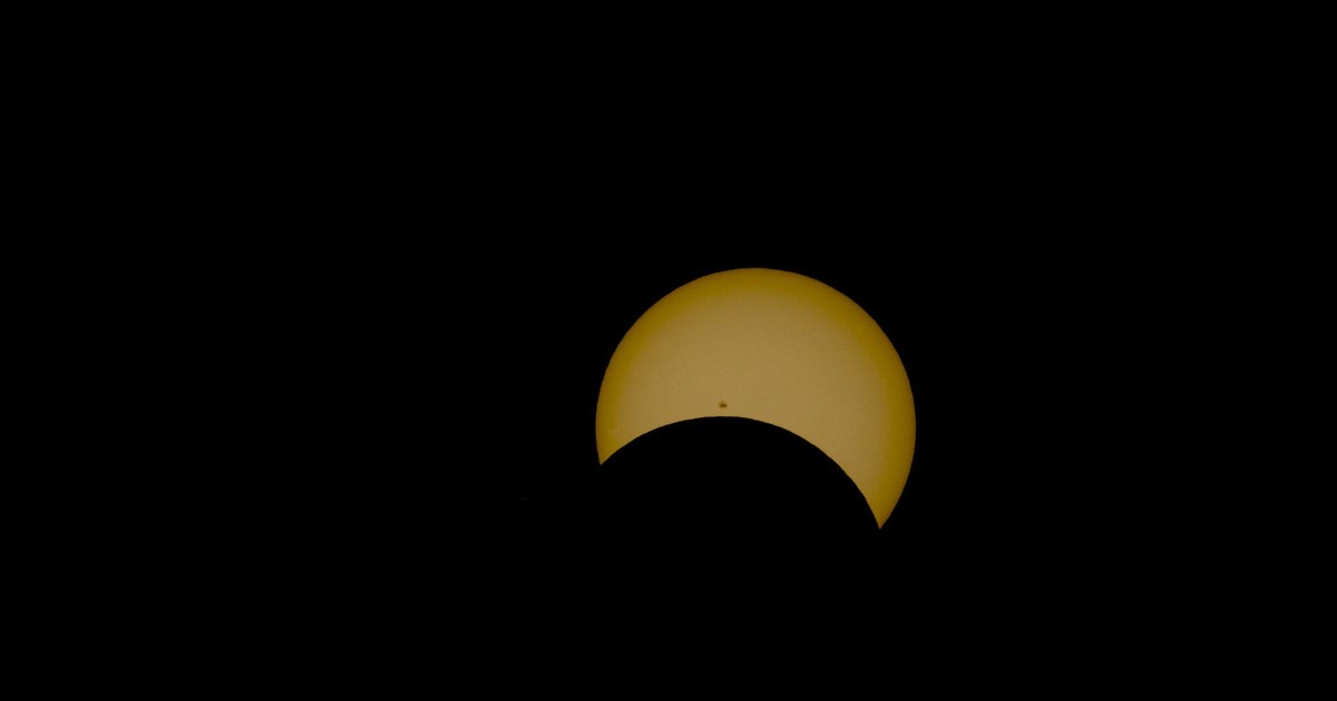 Dramatic partial solar eclipse showcasing a distinct sun spot against a dark sky.