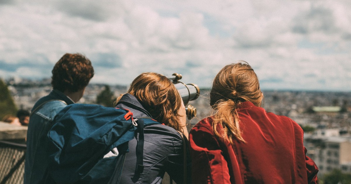 A group of young tourists exploring Paris views through a telescope during the day.