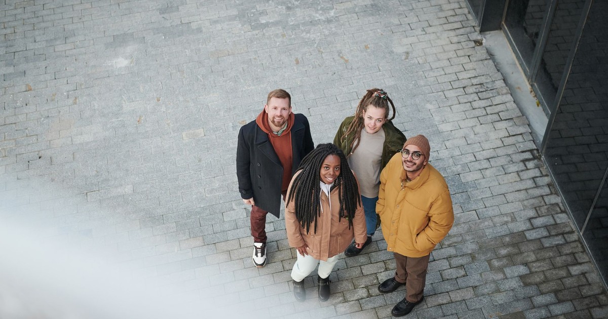 A diverse group of friends smiling while posing outdoors. Urban setting, daytime vibe.